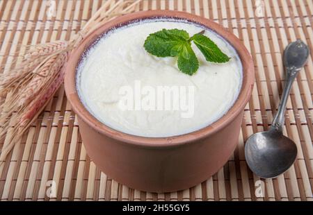 Natürlich, Joghurt in Auflaufschüssel auf Holztisch mit Löffel.Close Up taken.Turkish und Greek traditionelle Milchprodukte Joghurt oder angespannter Joghurt in Fass Stockfoto