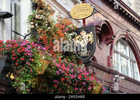 Logo und Blumenkörbe über den Argyll Arms im Oxford Circus, London, Großbritannien Stockfoto