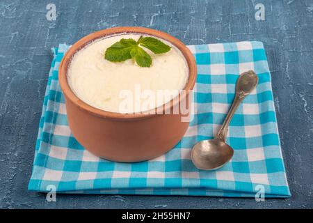 Rustik bir kapta ev yapımı yoğurt ve ekşi krema. Naturjoghurt in Auflaufschüssel auf Holztisch mit Löffel. Stockfoto