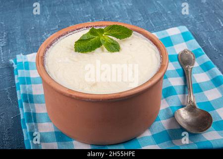 Rustik bir kapta ev yapımı yoğurt ve ekşi krema. Naturjoghurt in Auflaufschüssel auf Holztisch mit Löffel. Stockfoto