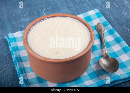 Rustik bir kapta ev yapımı yoğurt ve ekşi krema. Naturjoghurt in Auflaufschüssel auf Holztisch mit Löffel. Stockfoto