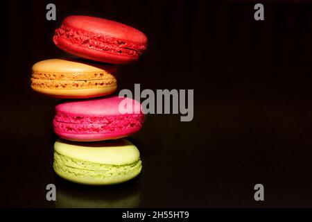 Bunte Mandelgebäck auf dunklem Hintergrund, Foto für jeden Zweck. Ort für Ihren Text. Kulinarisches und Süßwaren Fabrik Konzept. Makronen Stockfoto