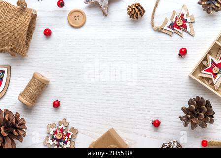 Weihnachtliche rustikale Komposition auf weißem Holzhintergrund mit Kopierraum. Weihnachtsschmuck, Tannenzapfen, Hagebutte, Sack. Flach liegend, Draufsicht Stockfoto