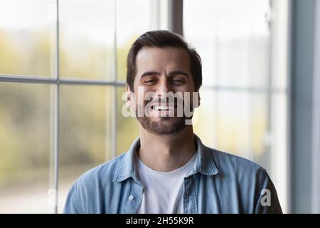 Headshot-Porträt eines lachenden jungen lässigen Mannes, der drinnen steht Stockfoto