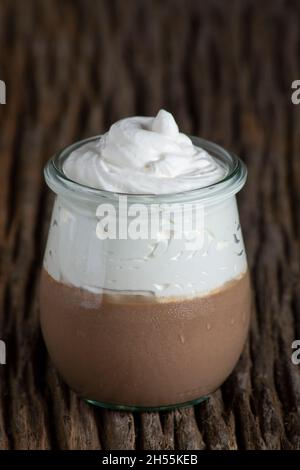 Ein Schokoladenmousse mit Creme auf einem antiken Holzbrett Stockfoto