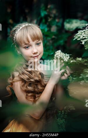 Schöne 11-jährige Mädchen mit langen blonden Haaren in Hortensien Blumen. Bild von einem charmanten kleinen Prinzessin Stockfoto