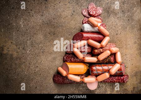 Weihnachtsbaum aus verschiedenen Wurstsorten, Salami und geräuchertem Fleisch mit Basilikum und Gewürzen auf Steingrund. Draufsicht. Stockfoto