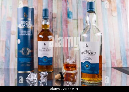 Zwei Flaschen Ben Bracken Single Malt Whiskey mit Glas und Eiswürfeln vor einem bunten Holzhintergrund Stockfoto