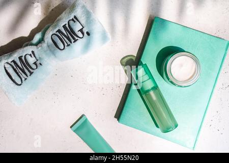 Gläser kosmetische Creme mit grünen Blättern, omg Haarband und Notizbuch minzfarben auf weiß mit Schatten, Oberkante Stockfoto