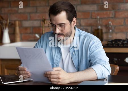 Besorgt tausendjährige Männer verwalten Papierdokumente, die mit statistischen Berichten beunruhigt sind Stockfoto