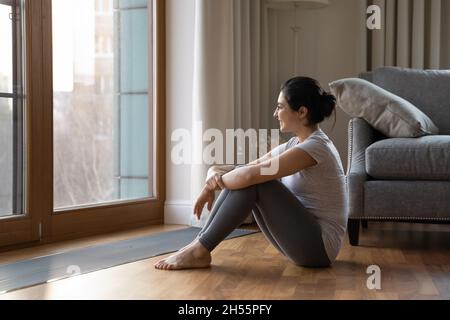 Indische Frau in Sportswear Entspannen Sie sich nach dem Training und schauen Sie aus dem Fenster Stockfoto