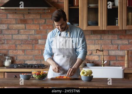 Millennial männlich trägt Küchenschürze kochen diätetischen Salat zum Frühstück Stockfoto