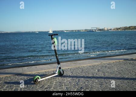 LISSABON, PORTUGAL - 30. Jul 2021: Ein Motorroller parkt in Ribeira das Naus an der Bucht des Flusses Tejo in Lissabon, Portugal Stockfoto