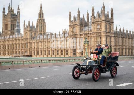 London, Großbritannien. November 2021. Teilnehmer an Oldtimern überqueren die Westminster Bridge während des London to Brighton Veteran Car Run. Mehr als 320 Oldtimer aus der Zeit vor 1905 nehmen am 125. Jahrestag der historischen Emancipation Run Teil, bei der die Übergabe der Lokomotiven auf dem Highway Act gefeiert wurde und die Geschwindigkeitsbegrenzung von 4 auf 14 km/h erhöht wurde. Verzicht auf die Notwendigkeit, dass Fahrzeuge von einem Mann mit roter Warnflagge vorausgehen, der Jahrhunderte des Pferdeverkehrs effektiv beendet und Autofahrern die Freiheit der Straße gibt. Kredit: Stephen Chung/Alamy Live Nachrichten Stockfoto