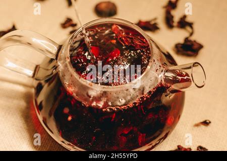 Gieße heißes kochendes Wasser in die Teekannen aus Glas. Rosafarbenen Tee zubereiten Stockfoto