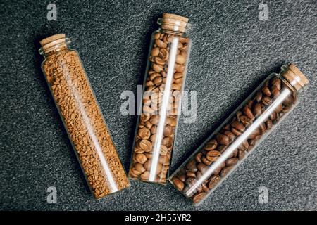 Draufsicht auf verschiedene Kaffeebohnen in drei Mini-Glasflaschen Stockfoto