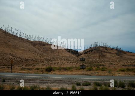 Landschaft mit Windkraftanlagen in Reihen auf einem Hügel | Foto des Windparks vom Autofahren, Fensteransichten auf der Straße Stockfoto