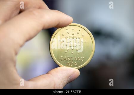 Die Münze von Cardano Ada wird zwischen zwei Fingern gehalten Stockfoto