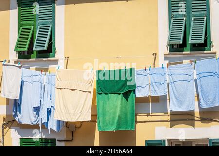 Eine Gruppe von Handtüchern und Bademänteln, die vor dem Fenster an einer Wäscheleine hingen, um in der Sonne zu trocknen. Tellaro Dorf, Ligurien, Italien, Südeuropa. Stockfoto