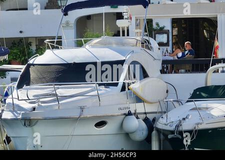 Almuñécar, Spanien; 28. Oktober 2021: Zwei Personen bei einem Glas Wein neben einer Yacht in der Marina Almuñécar in Granada (Spanien) Stockfoto