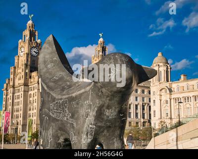 Eine SuperLambBanana-Statue am Pier Head am River Mersey in Liverpool. An einem sonnigen Tag mit blauem Himmel erscheint das Lebergebäude im Hintergrund. Stockfoto