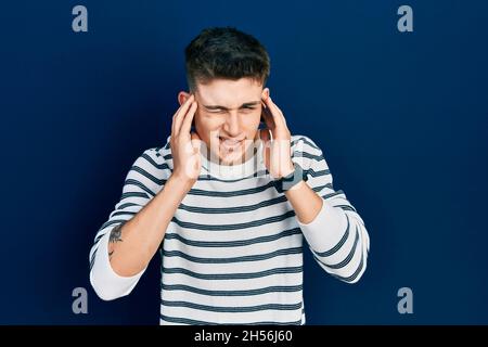 Junge kaukasische Junge mit Ohren Erweiterung tragen lässige gestreifte Hemd bedeckt Ohren mit Fingern mit verärgerten Ausdruck für den Lärm der lauten Musik. De Stockfoto