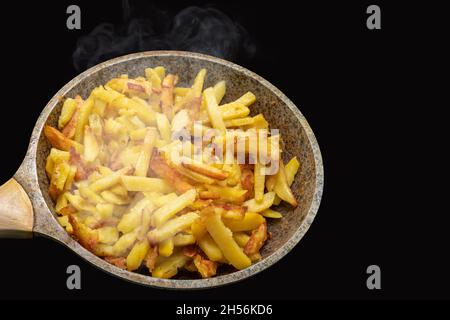 Köstliche knusprige, goldheiße, gebratene Kartoffelkeile auf einer alten Metallpfanne in Nahaufnahme. Dampfen von frisch gekochten hausgemachten Bratkartoffeln in der Bratpfanne iso Stockfoto