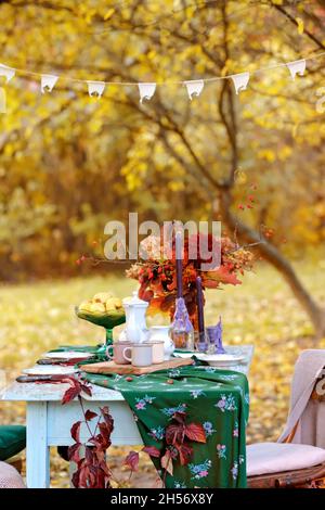 Herbstthema Feiertagstisch Anordnung für eine saisonale Party, Tassen, Äpfel, Kerzen, Feldblumen. Thanksgiving Tag Party Dekoration oder romantische Herbst Garten Picknick Stockfoto