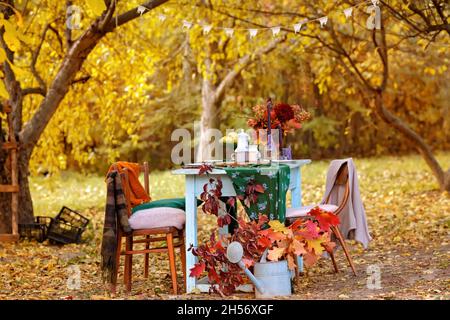 Herbstthema Feiertagstisch Anordnung für eine saisonale Party, Tassen, Äpfel, Kerzen, Feldblumen. Thanksgiving Tag Party Dekoration oder romantische Herbst Garten Picknick Stockfoto