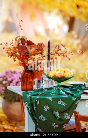 Herbstthema Feiertagstisch Anordnung für eine saisonale Party, Tassen, Äpfel, Kerzen, Feldblumen. Thanksgiving Tag Party Dekoration oder romantische Herbst Garten Picknick Stockfoto