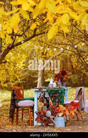 Herbstthema Feiertagstisch Anordnung für eine saisonale Party, Tassen, Äpfel, Kerzen, Feldblumen. Thanksgiving Tag Party Dekoration oder romantische Herbst Garten Picknick Stockfoto