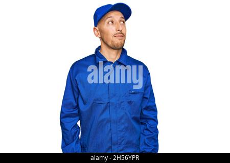 Glatze Mann mit Bart tragen Baumeister Jumpsuit Uniform lächeln zur Seite schauen und starren weg denken. Stockfoto