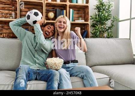 Junges Paar beim Fußballspiel beim Essen von Porpcorn zu Hause. Stockfoto