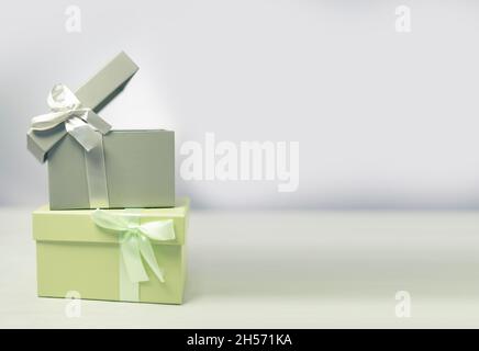 Pastellgrüne und graue Geschenkschachteln stehen übereinander mit weißem Hintergrund, mit Kopierfläche. Stockfoto