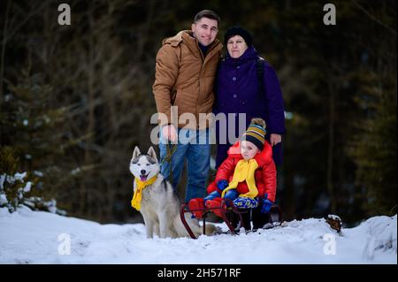 Familie in dritter Generation Großmutter, Sohn und Enkelin im Winterwald, ihr Husky Dog, Schlittenmädchen.neu Stockfoto