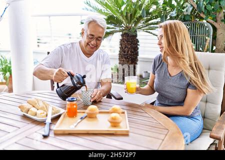 Das hispanische Paar mittleren Alters lächelte und freute sich beim Frühstück auf der Terrasse. Stockfoto