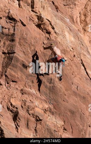 Ein Sportkletterer auf Lead fällt von der Mauer, die das Theater in der Nähe von Moab, Utah, genannt wird. Stockfoto