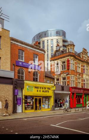 Blick auf die Dalston High Street, mit dem zeitgenössischen Apartmentgebäude FiftySevenEast, das über älteren Gebäuden thront und sich mit älteren Gebäuden konfrontiert zeigt. Stockfoto