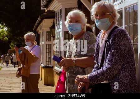 Eine kleine Gruppe älterer Touristen besucht den Broadway in den Cotswolds. Sie tragen Gesichtsmasken als zusätzlichen Schutz vor dem Covid 19-Virus. Stockfoto