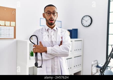 afroamerikanischer Arzt, der Stethoskop in der Klinik im Schockgesicht hielt, skeptisch und sarkastisch aussachte, überrascht mit offenem Mund Stockfoto