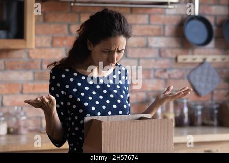 Die gerissenen lateininnen erhalten beschädigte Waren im Lieferkarton Stockfoto