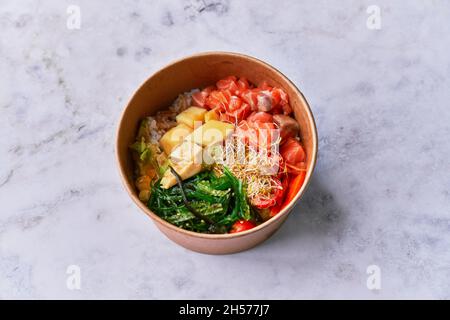 Köstliche Take-Away-Poke-Schüssel auf einer Marmoroberfläche Stockfoto
