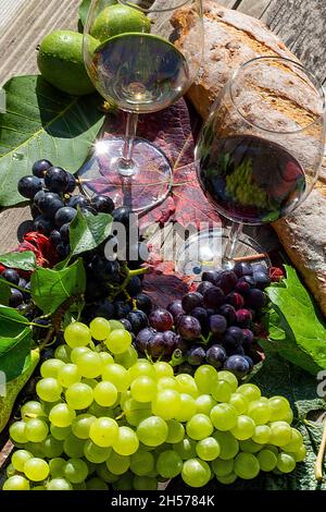 Symbolbild der Weinlese: Reife Trauben, verziert mit Weingläsern auf einem Holztisch Stockfoto