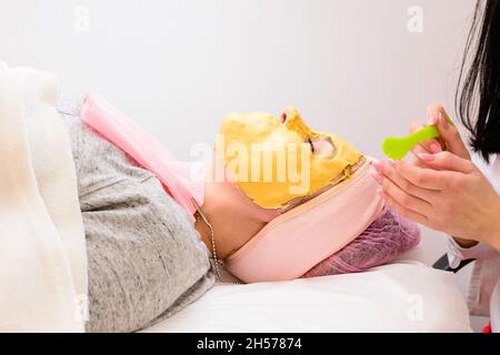 Der Prozess der Entfernung der kosmetischen goldenen Masse, kosmetische Verfahren im Salon. Neu Stockfoto