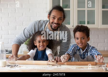 Happy Black Papa hilft Kindern in Schürzen Kuchen backen Stockfoto