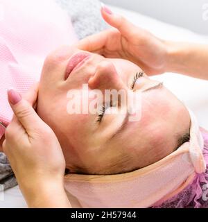 Glückliche und entspannte Frau auf Kosmetologie Verfahren, Massage und Anwendung Gesichtscreme. Neu Stockfoto