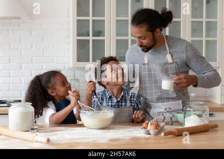 Glückliche Kinder und junger Vater tragen Schürzen, Kochen Backwaren Stockfoto