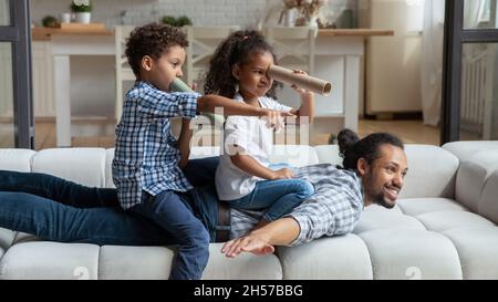 Glücklicher Dagd und Kinder spielen lustige aktive Spiele auf der Couch Stockfoto