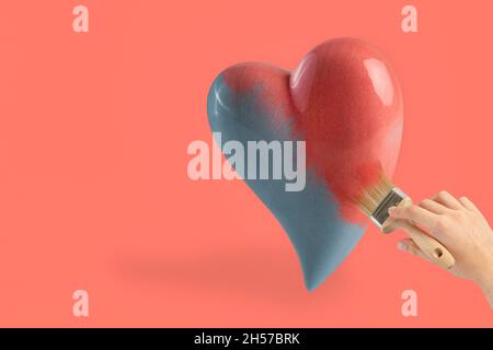 Rosa Herz auf einem rosa Hintergrund. Eine Männerhand malt ein schwarz-weißes Herz in Rosa mit einem Pinsel mit rosa Farbe. Valentinstag-Konzept. Stockfoto