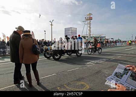 Brighton, East Sussex, Großbritannien. November 2021. Ein 1903 Renault erreicht die Ziellinie, als jemand auf einem Reißdraht beim 125. London to Brighton Veteran Car Run in Madeira Drive, Brighton, East Sussex, Großbritannien, vorbeikommt. © Malcolm Greig/Alamy Live News Stockfoto